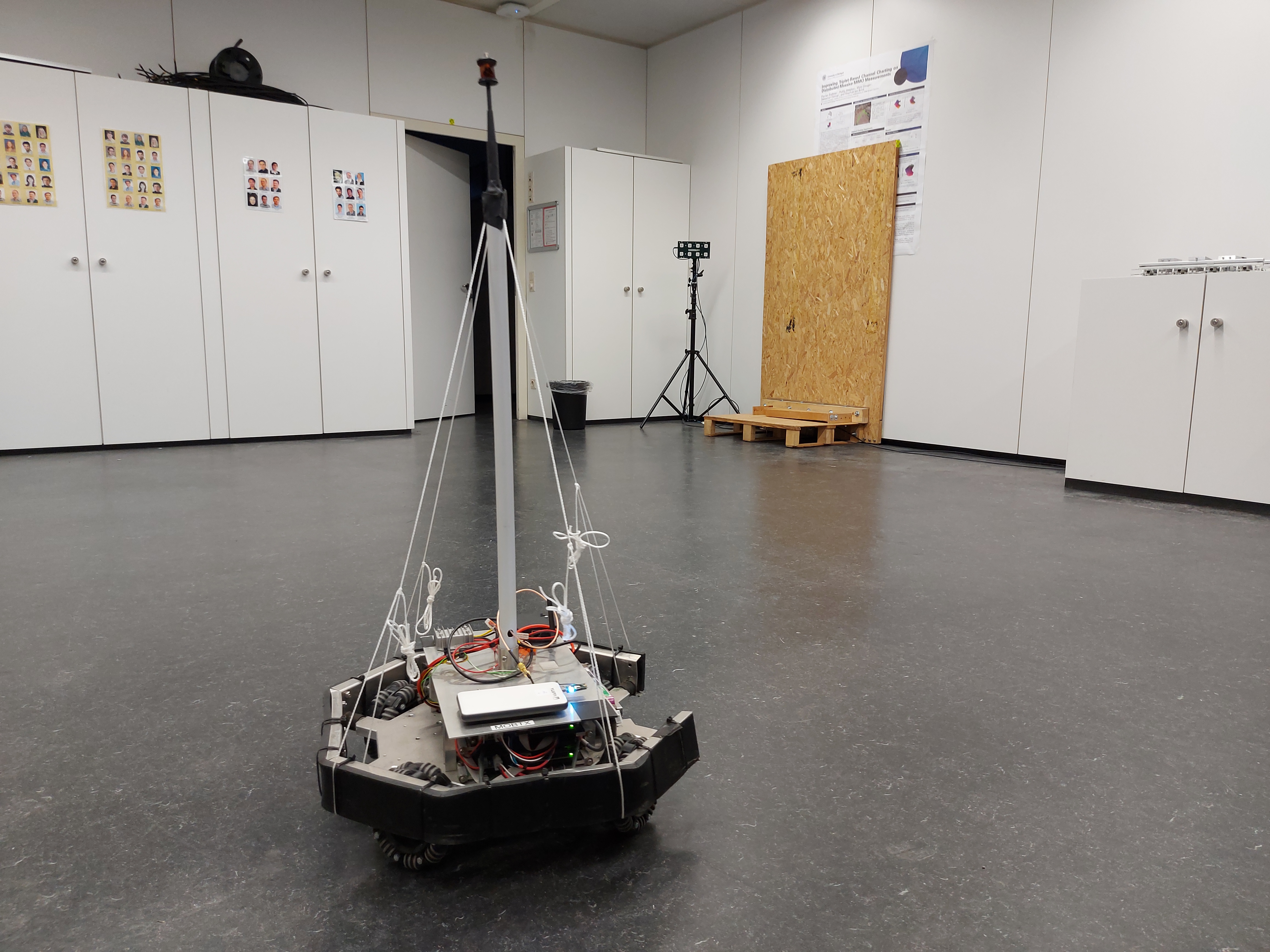 Robot with antenna and prism for tracking, ESPARGOS array and door in the background.